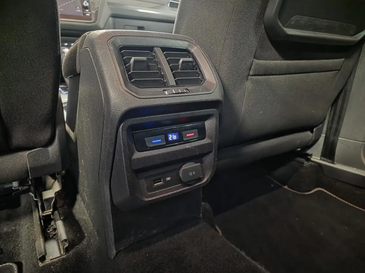 Vue rapprochée de la console arrière noire du Volkswagen Tiguan 2019 avec sorties d'air, réglage de température et prises USB et 12V.