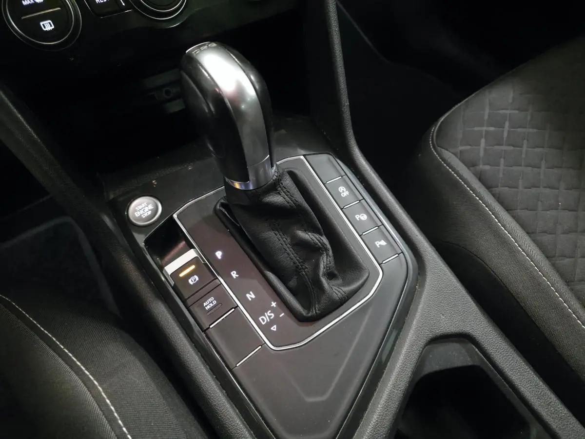 Gros plan sur le levier de vitesses automatique noir et argenté du Volkswagen Tiguan 2019, avec siège tissu gris à motifs.