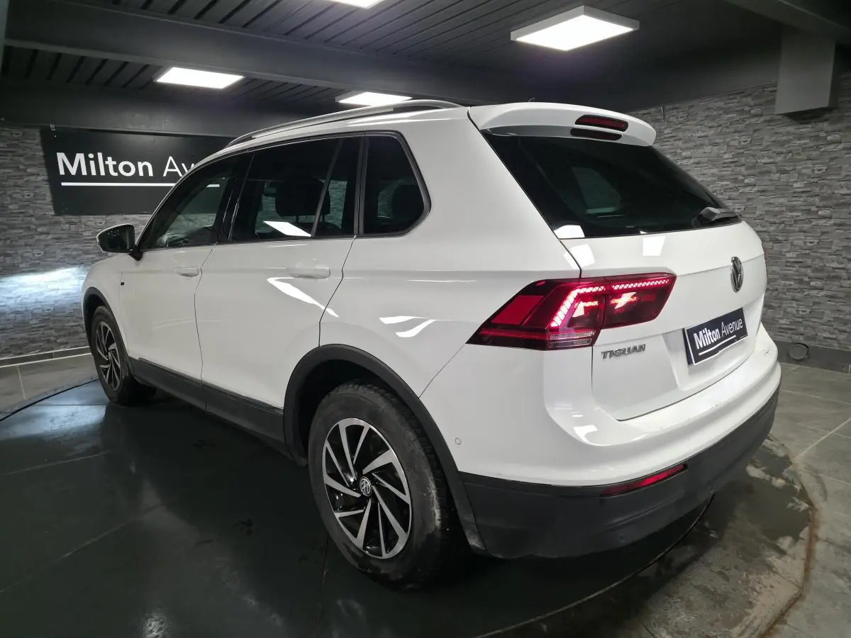 Volkswagen Tiguan blanc vue 3/4 arrière droit avec feux LED et jantes alliage 17 pouces en intérieur showroom.