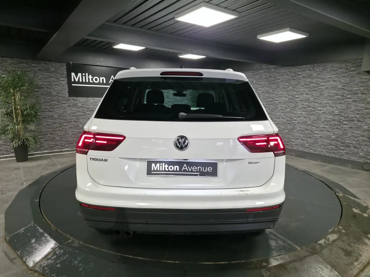 Vue arrière d'un Volkswagen Tiguan blanc avec feux LED allumés dans un showroom intérieur.