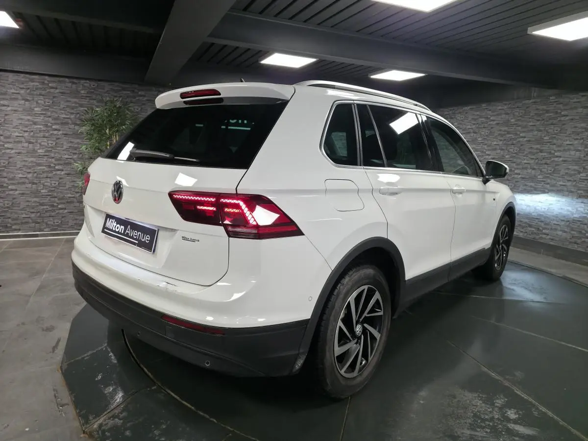 Vue 3/4 arrière droit d'un Volkswagen Tiguan blanc avec feux arrière LED et jantes alliage 17 pouces.