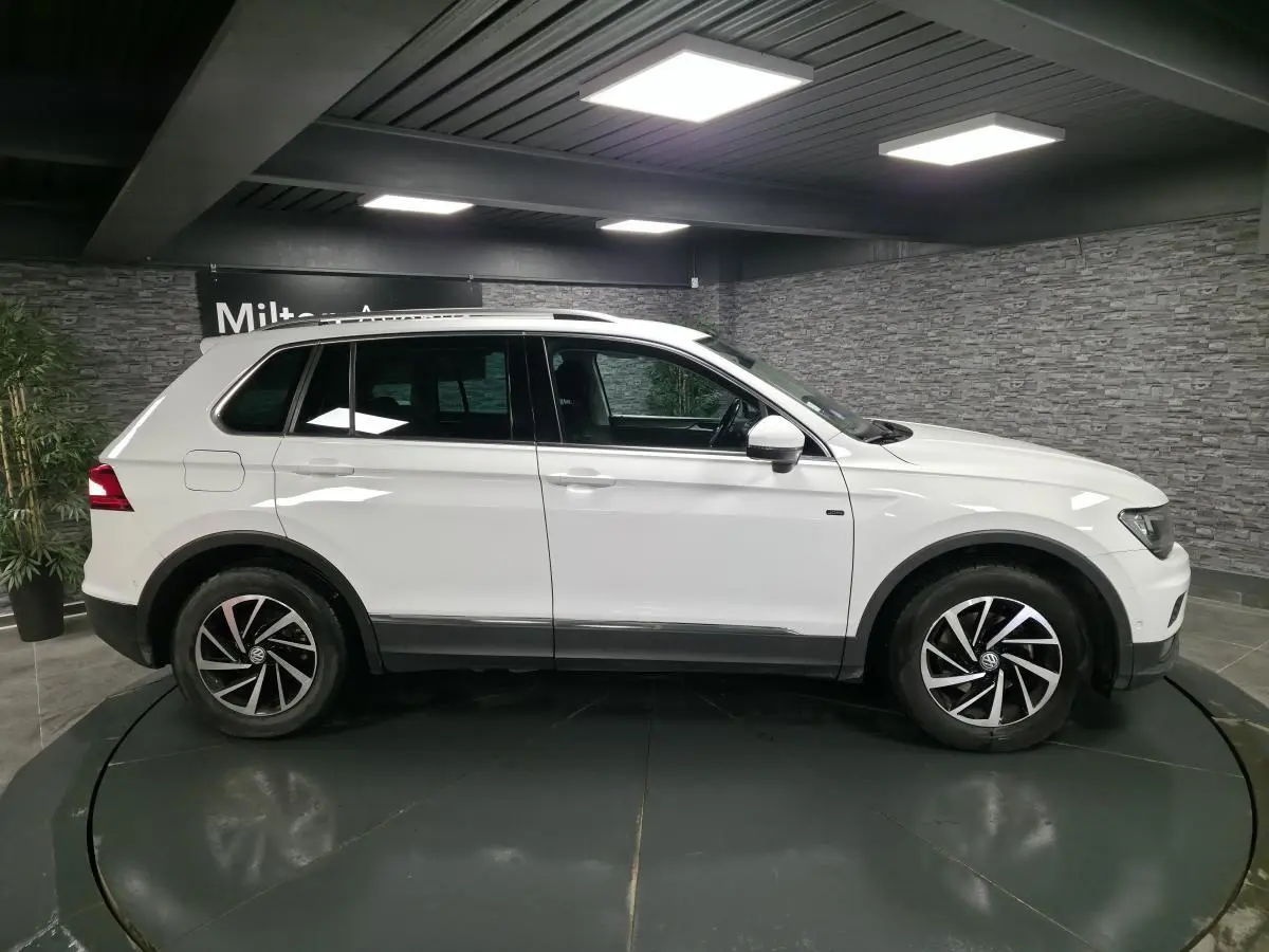 Volkswagen Tiguan blanc vue de profil côté gauche, avec jantes alliage noires et toit ouvrant visible.