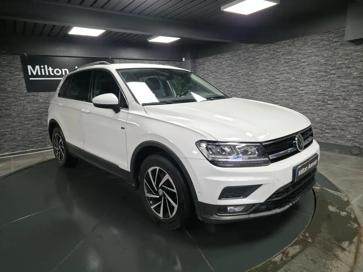 Volkswagen Tiguan blanc en 3/4 avant droit, avec jantes alliage et projecteurs LED allumés.