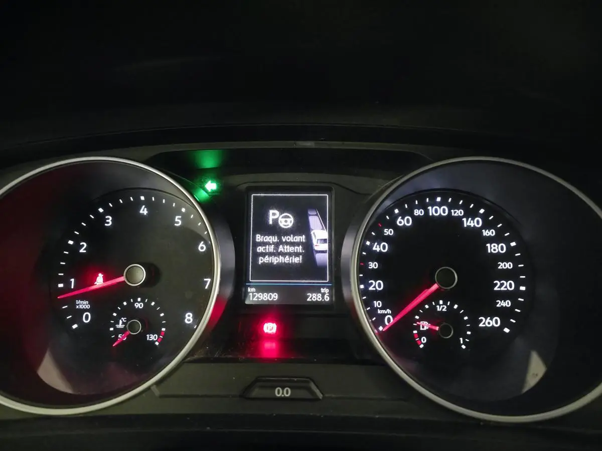 Vue rapprochée du tableau de bord du Volkswagen Tiguan blanc, affichant compte-tours, vitesse et alertes numériques.