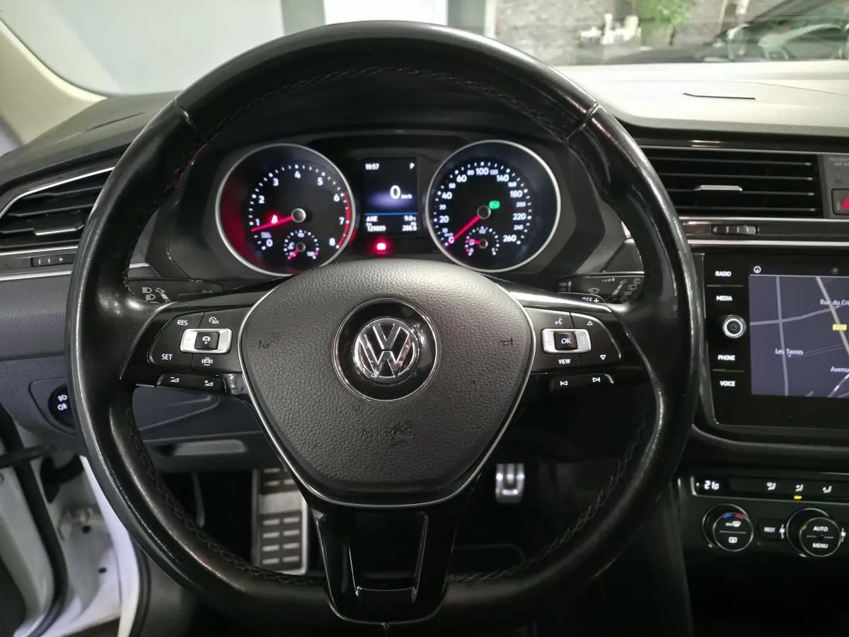 Vue rapprochée du volant en cuir noir et du tableau de bord numérique du Volkswagen Tiguan blanc 2019.