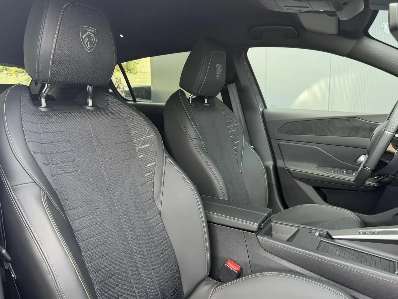 Vue intérieure côté droit sur les sièges tissu noir embossé avec surpiqûres vert Adamite de la Peugeot 308 GT Hybrid 2026.