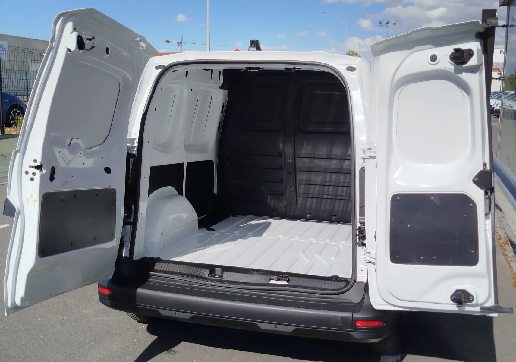 Vue arrière du Renault Kangoo blanc Minéral 2023 avec portes battantes ouvertes dévoilant l’espace de chargement vide.