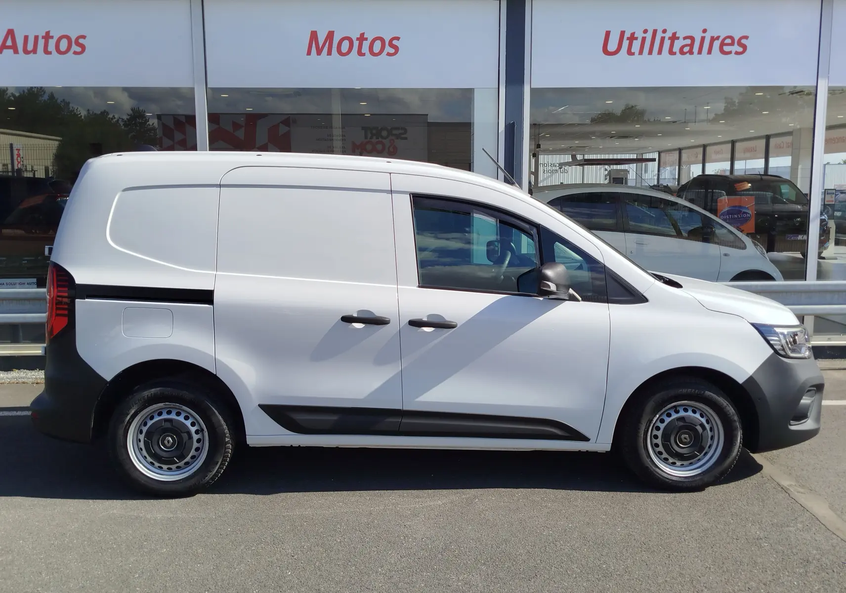 Vue latérale droite d’un utilitaire Renault Kangoo blanc minéral 2023 avec jantes acier et poignées noires.