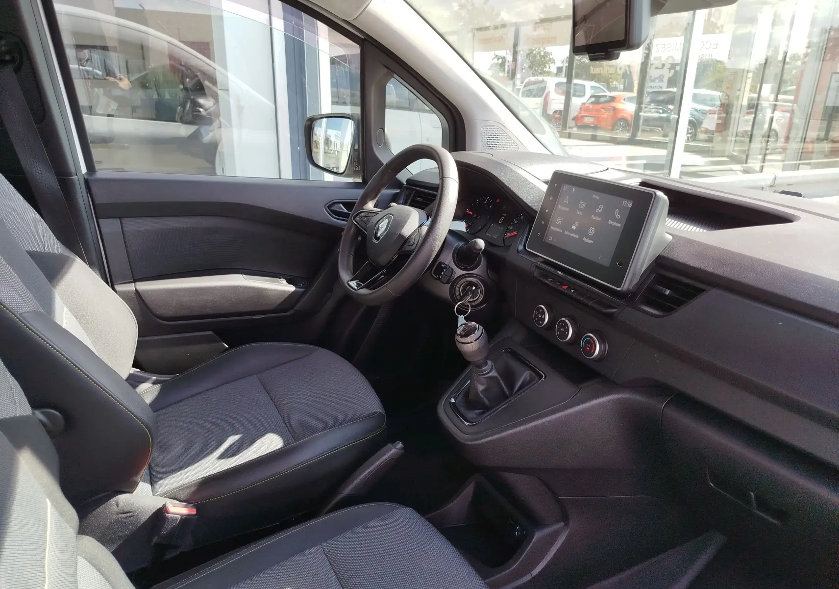 Vue intérieure côté conducteur du Renault Kangoo 2023, tableau de bord noir avec écran tactile et volant multifonction.