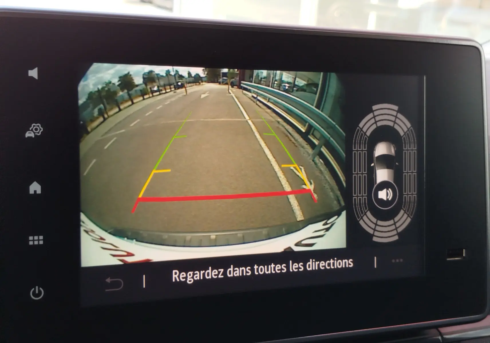Vue caméra de recul du Renault Kangoo blanc Minéral, affichant les lignes de guidage colorées et l'environnement arrière du véhicule.