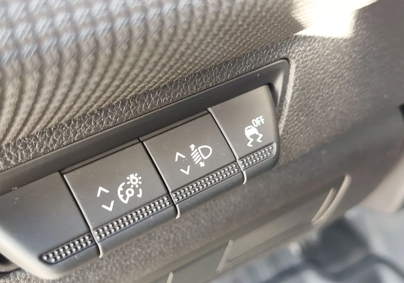Gros plan sur les boutons de réglage de l'éclairage et de l'ESP dans un Renault Kangoo blanc minéral 2023.