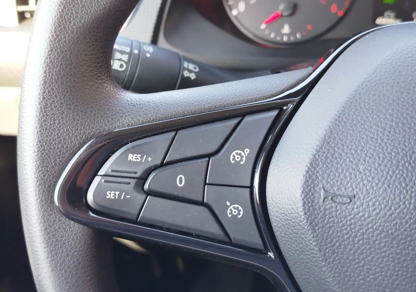 Gros plan sur les commandes de régulateur de vitesse à gauche du volant du Renault Kangoo blanc 2023.