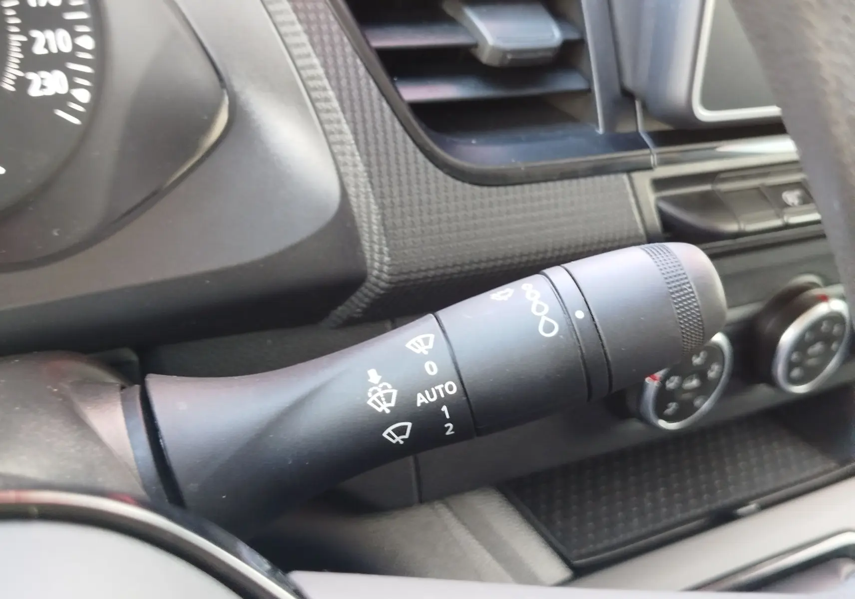 Gros plan sur la manette d’essuie-glace noire du tableau de bord intérieur du Renault Kangoo blanc 2023.