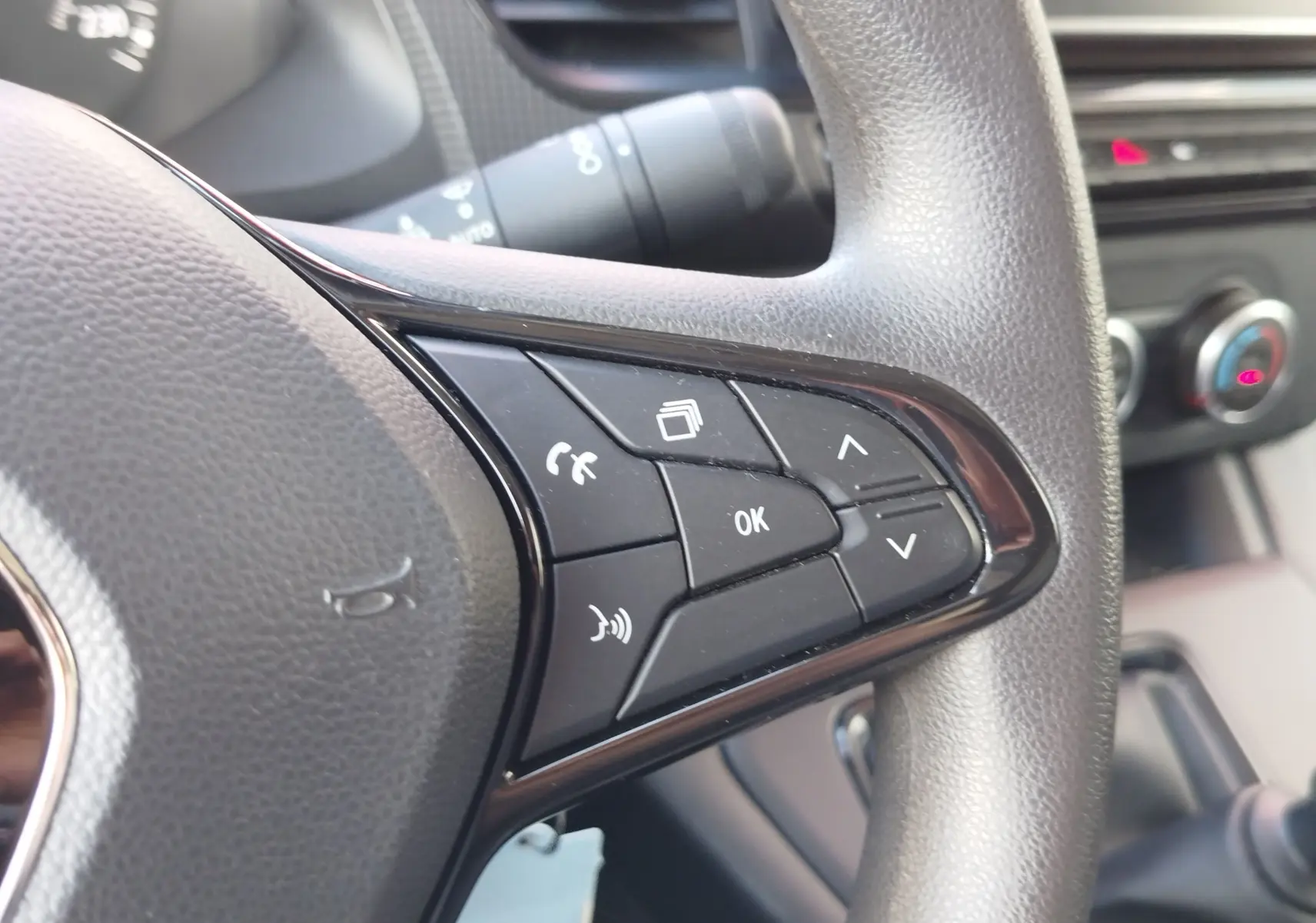 Gros plan sur les commandes multifonctions noires à droite du volant du Renault Kangoo 2023, intérieur gris.