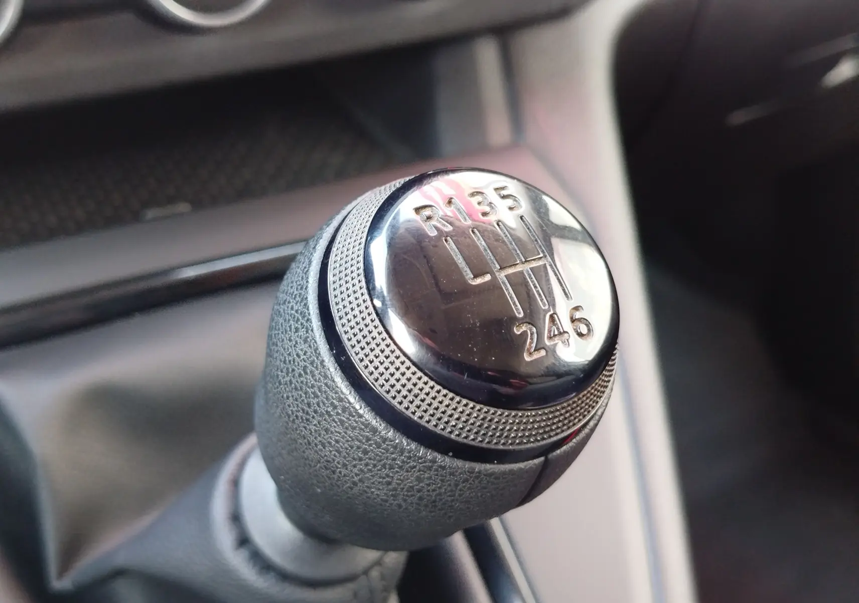 Gros plan sur le pommeau de la boîte manuelle du Renault Kangoo 2023, détail du levier de vitesses en cuir gris.