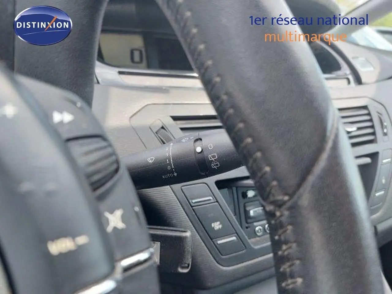 Gros plan sur le volant en cuir noir et la commande d'essuie-glace du tableau de bord intérieur d'une Citroën C4 Picasso 2013.