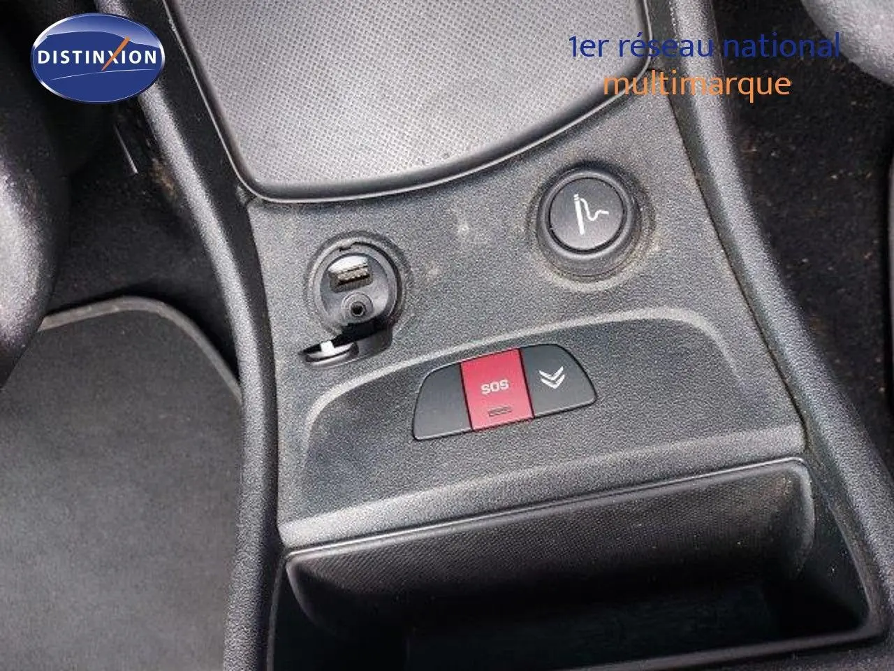Gros plan sur la console centrale d'une Citroën C4 Picasso gris alu, montrant les boutons SOS et de réglage siège.