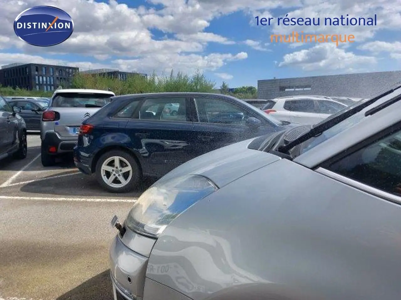 Vue rapprochée du côté avant droit d'une Citroën C4 Picasso gris alu métal sous un ciel partiellement nuageux.