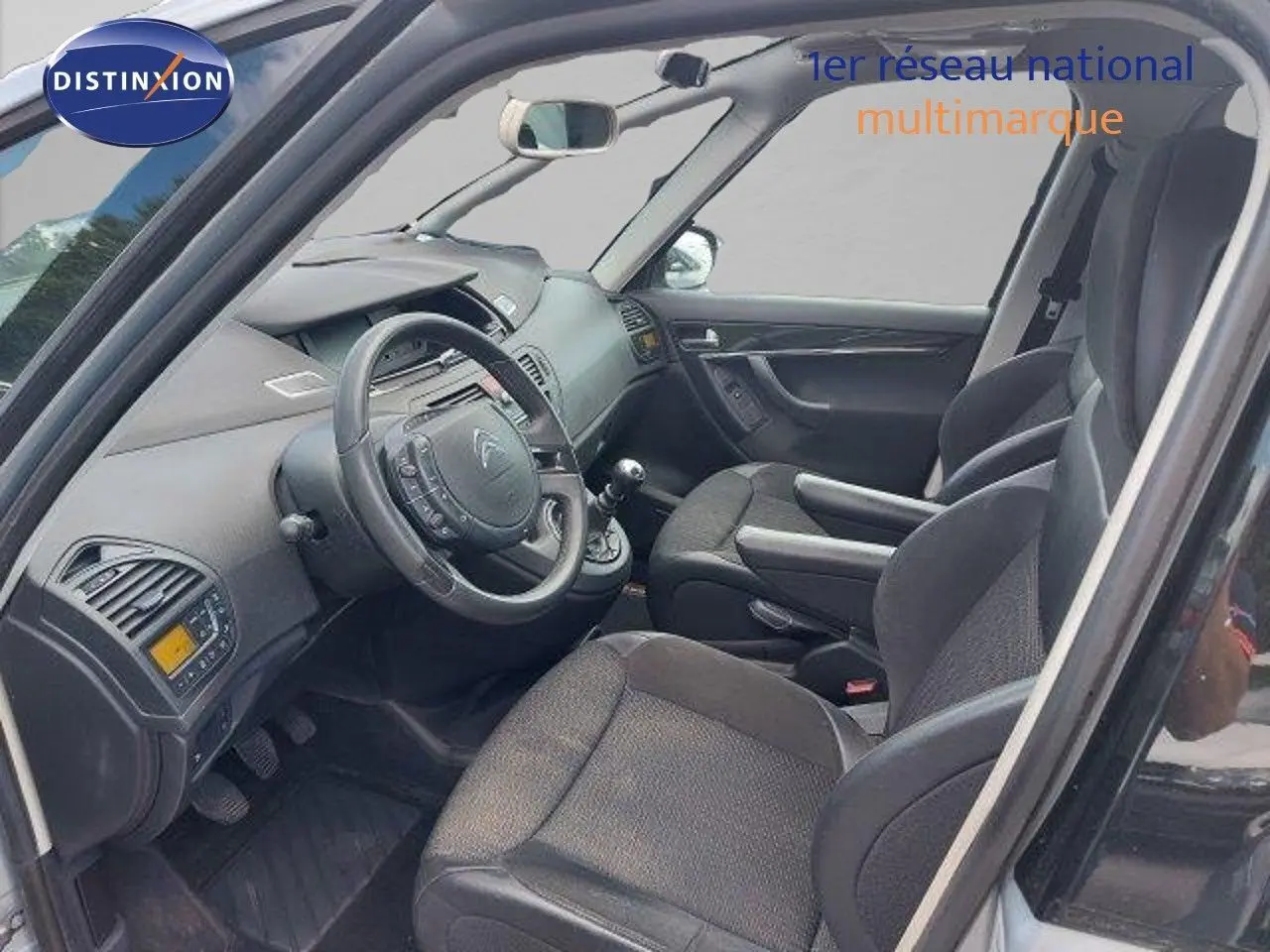 Intérieur avant droit de la Citroën C4 Picasso gris alu 2013, sièges tissu noir et tableau de bord complet.