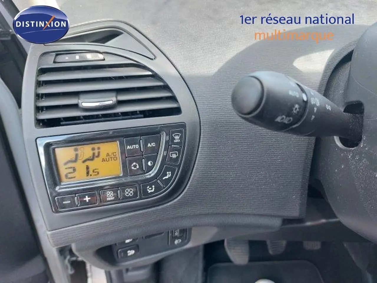 Détail du tableau de bord côté gauche avec commandes de climatisation numérique d'une Citroën C4 Picasso gris alu 2013.