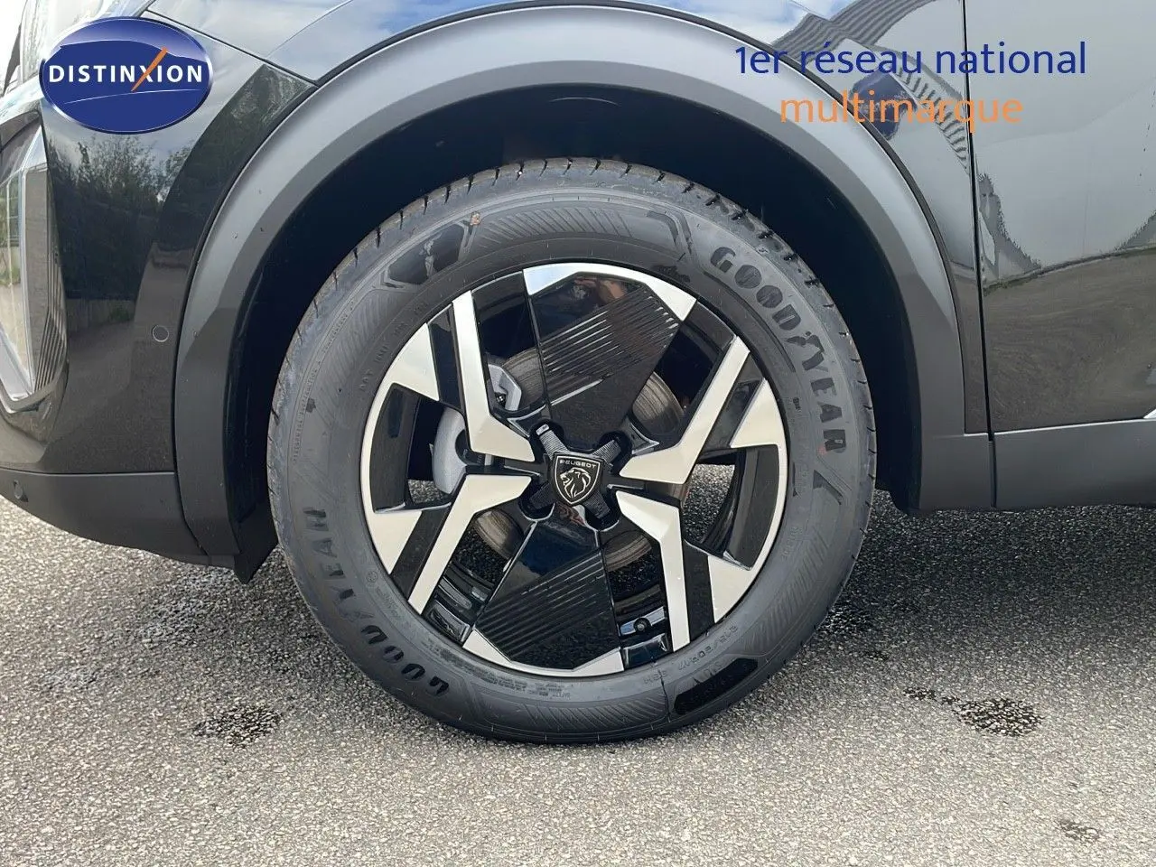 Gros plan sur la roue avant gauche du Peugeot 2008 noir Perla Metal avec jante alliage bicolore et pneu Goodyear.