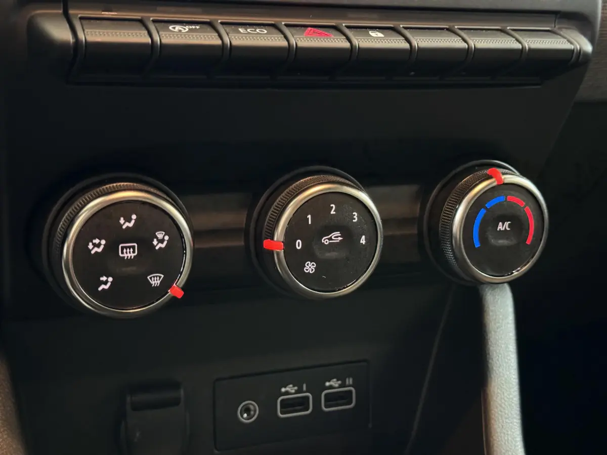 Gros plan sur les commandes de climatisation et les ports USB du tableau de bord de la Renault Clio gris clair 2025.