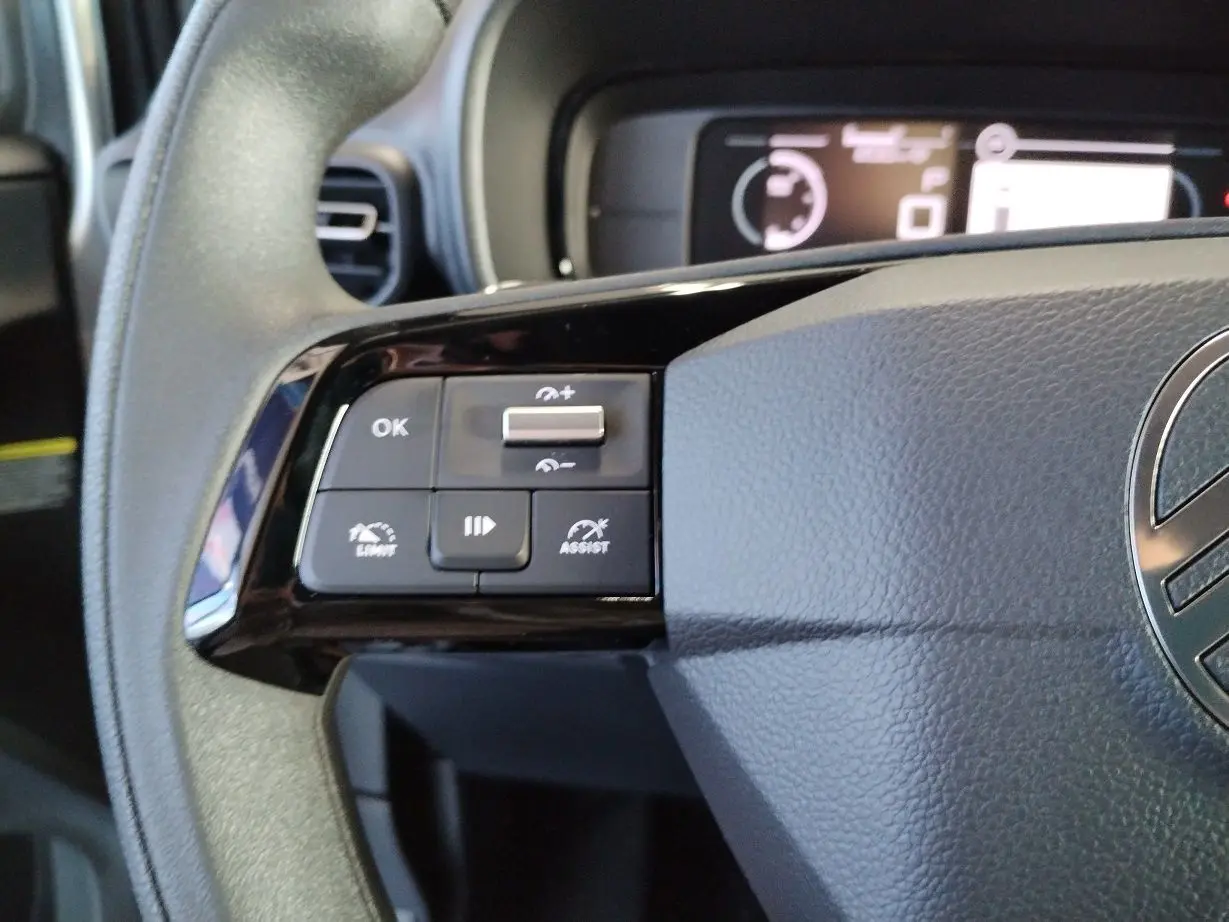 Gros plan sur les commandes à gauche du volant gris du Citroën Berlingo 2025 avec affichage numérique en arrière-plan.