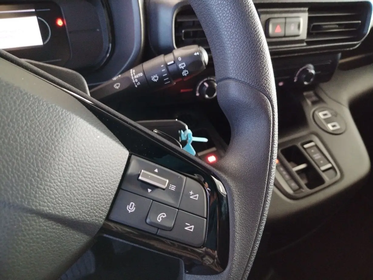 Gros plan sur le volant et la commande multifonction du Citroën Berlingo Van gris acier 2025 côté gauche.