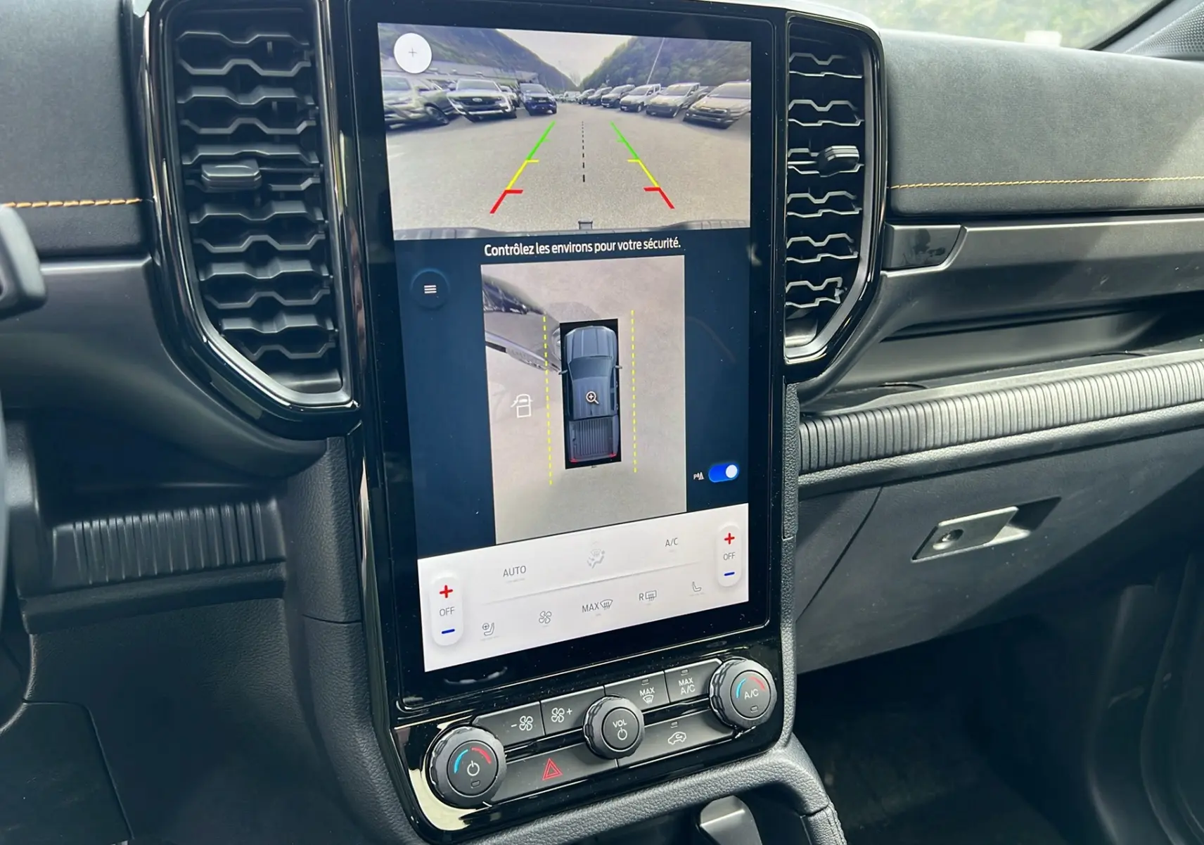 Vue rapprochée de la console centrale du Ford Ranger Wildtrak noir, avec écran tactile affichant la caméra 360° et commandes climatisation.
