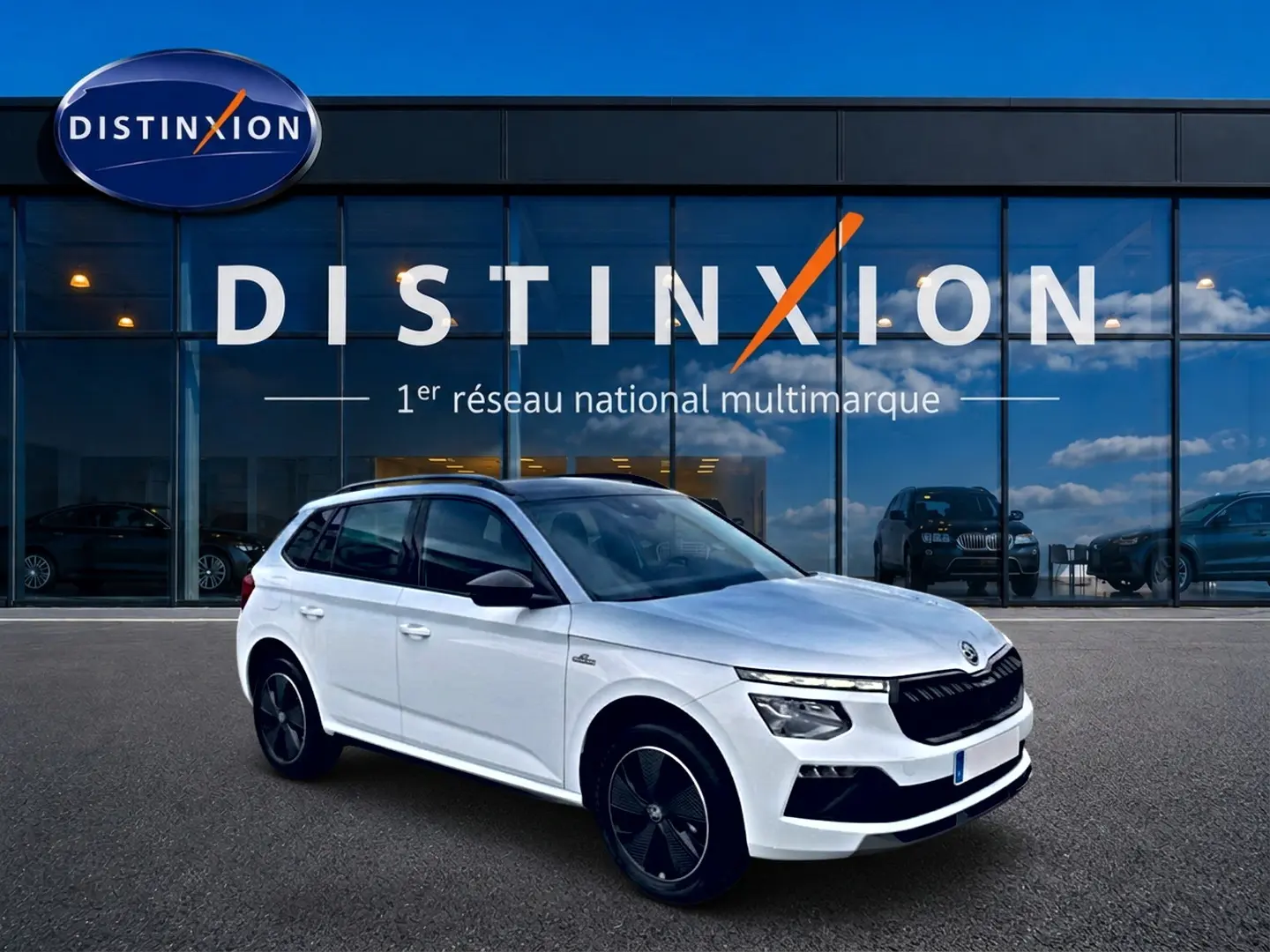 Vue 3/4 avant droite d'un Skoda Kamiq blanc nacré avec toit noir et jantes noires devant un showroom Distinxion.