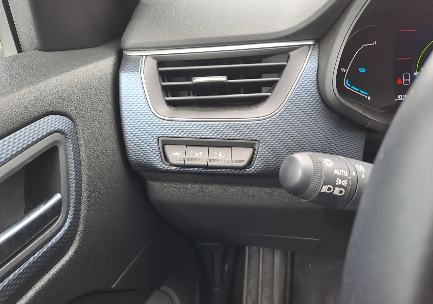 Détail de la console gauche avec aérateur et commandes d'assistance sur fond bleu Zanzibar métal dans un Renault Arkana hybride 2023.