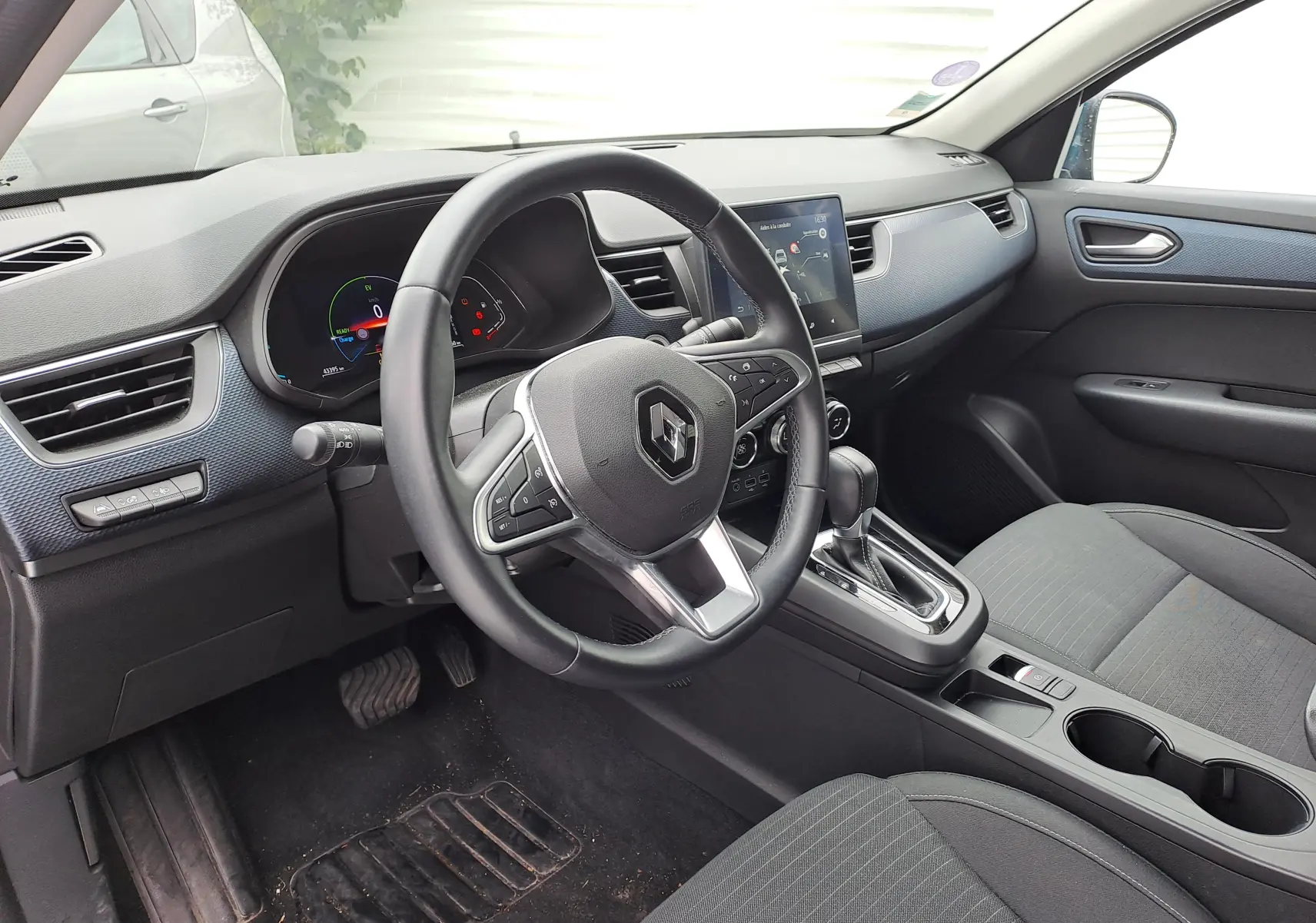 Intérieur noir du Renault Arkana 2023, vue côté conducteur sur le volant, tableau de bord digital et console centrale.