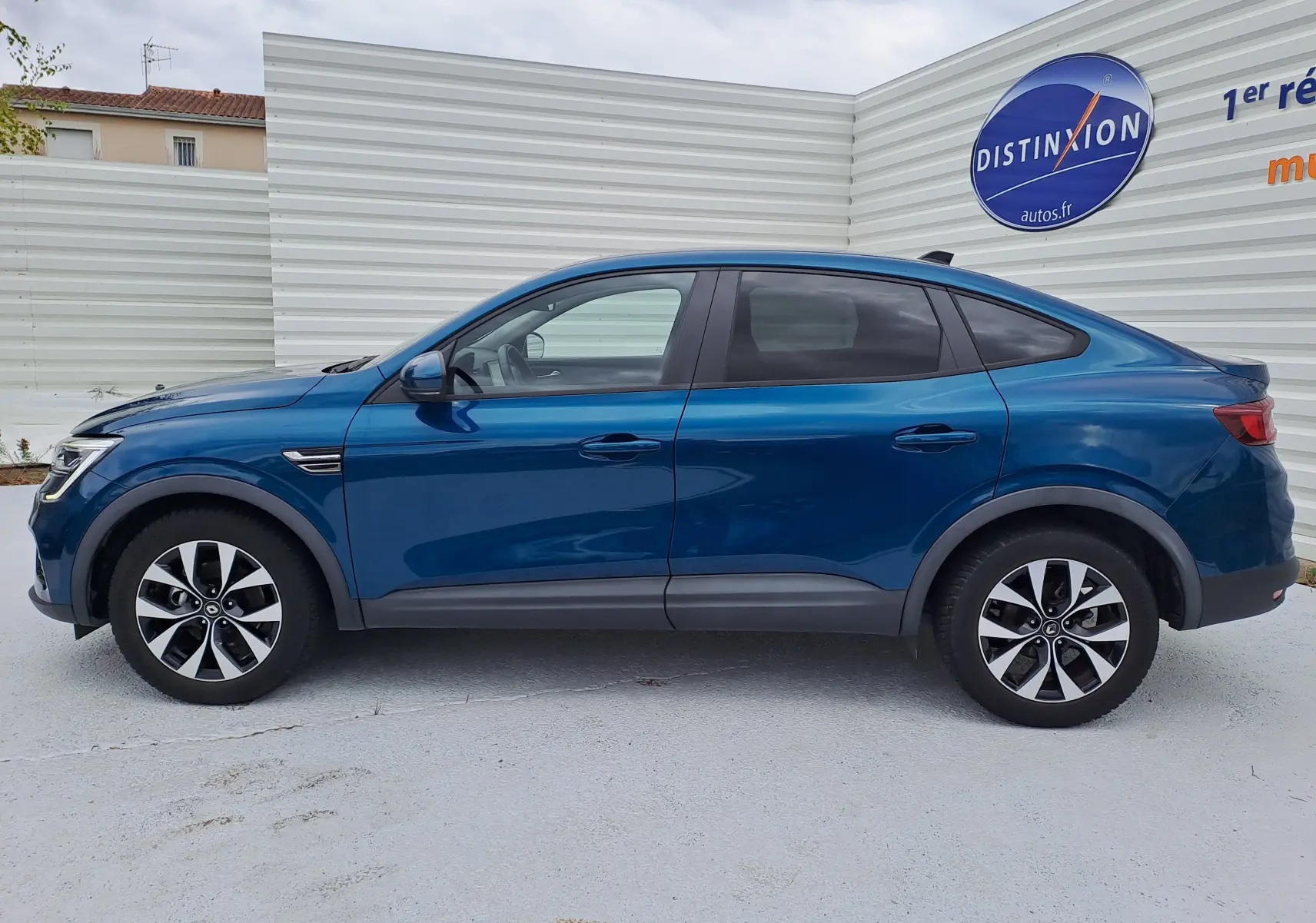 Profil côté gauche d'un Renault Arkana bleu Zanzibar metal 2023, SUV hybride avec jantes bi-ton et lignes fluides.