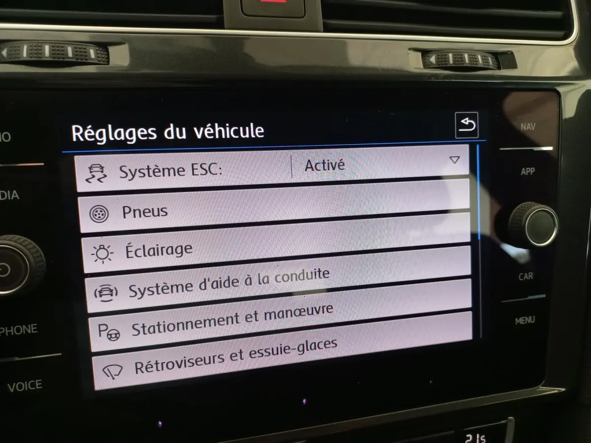 Écran tactile central affichant les réglages du véhicule dans une Volkswagen Golf gris foncé, vue intérieure rapprochée.