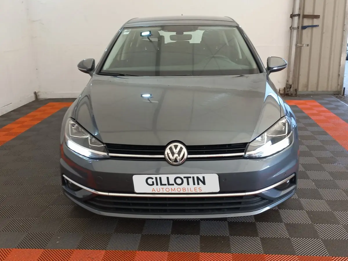 Vue frontale d'une Volkswagen Golf gris foncé 2019 avec phares LED et plaque GILLOTIN Automobiles.