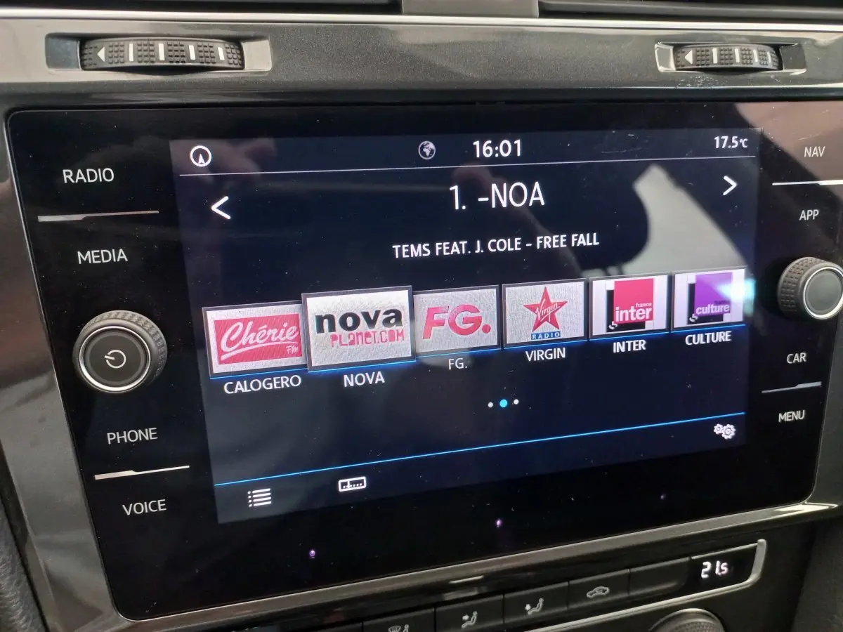 Écran tactile central de la Volkswagen Golf gris foncé 2019 affichant les stations radio et la chanson en cours.