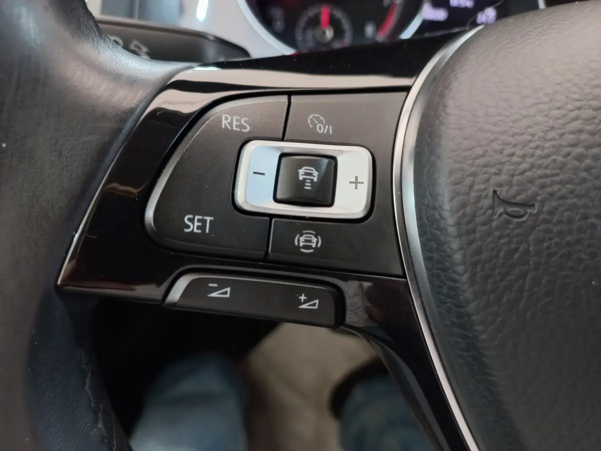 Gros plan sur les commandes du régulateur de vitesse au volant cuir noir de la Volkswagen Golf gris foncé 2019.