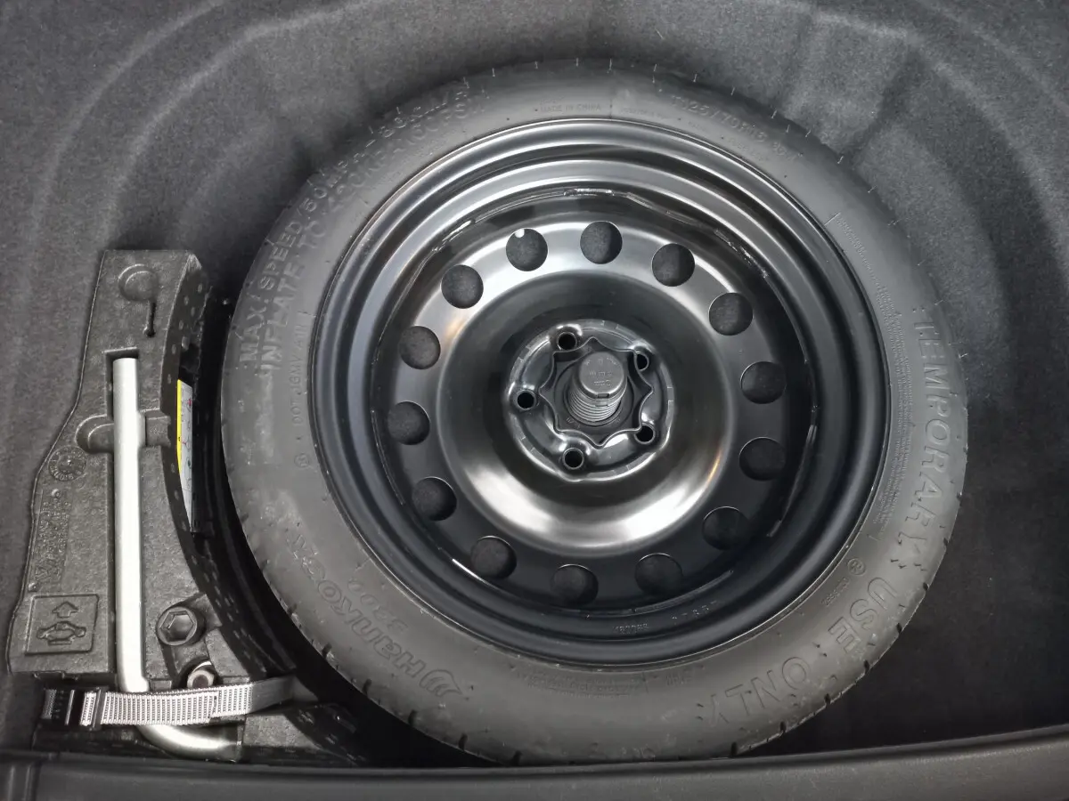 Roue galette noire de secours dans le coffre d'une Volkswagen Golf 1.0 TSI 115 DSG7 Confort Business gris foncé.