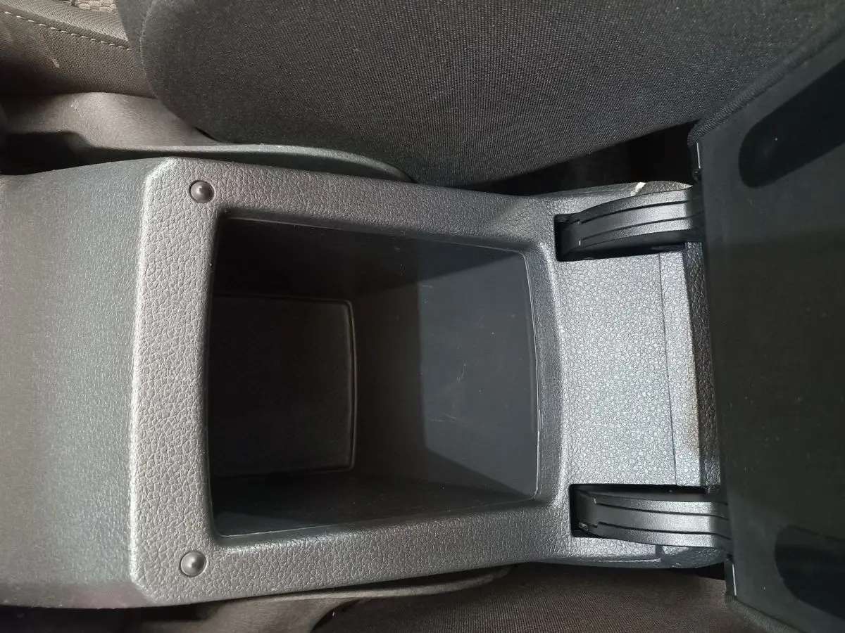 Gros plan sur le rangement central ouvert entre les sièges avant d'une Volkswagen Golf gris foncé de 2019.