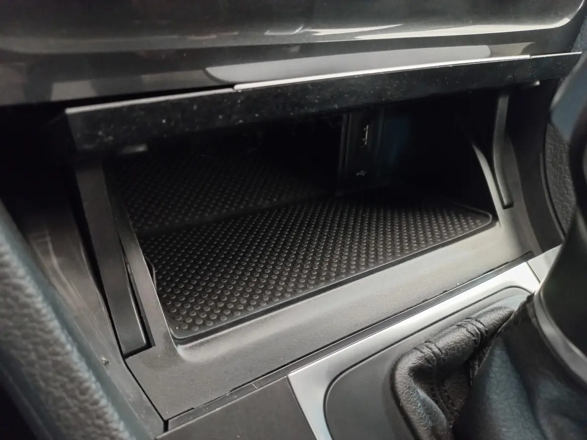 Rangement ouvert côté passager avec prise USB et console centrale en cuir noir dans une Volkswagen Golf gris foncé 2019.