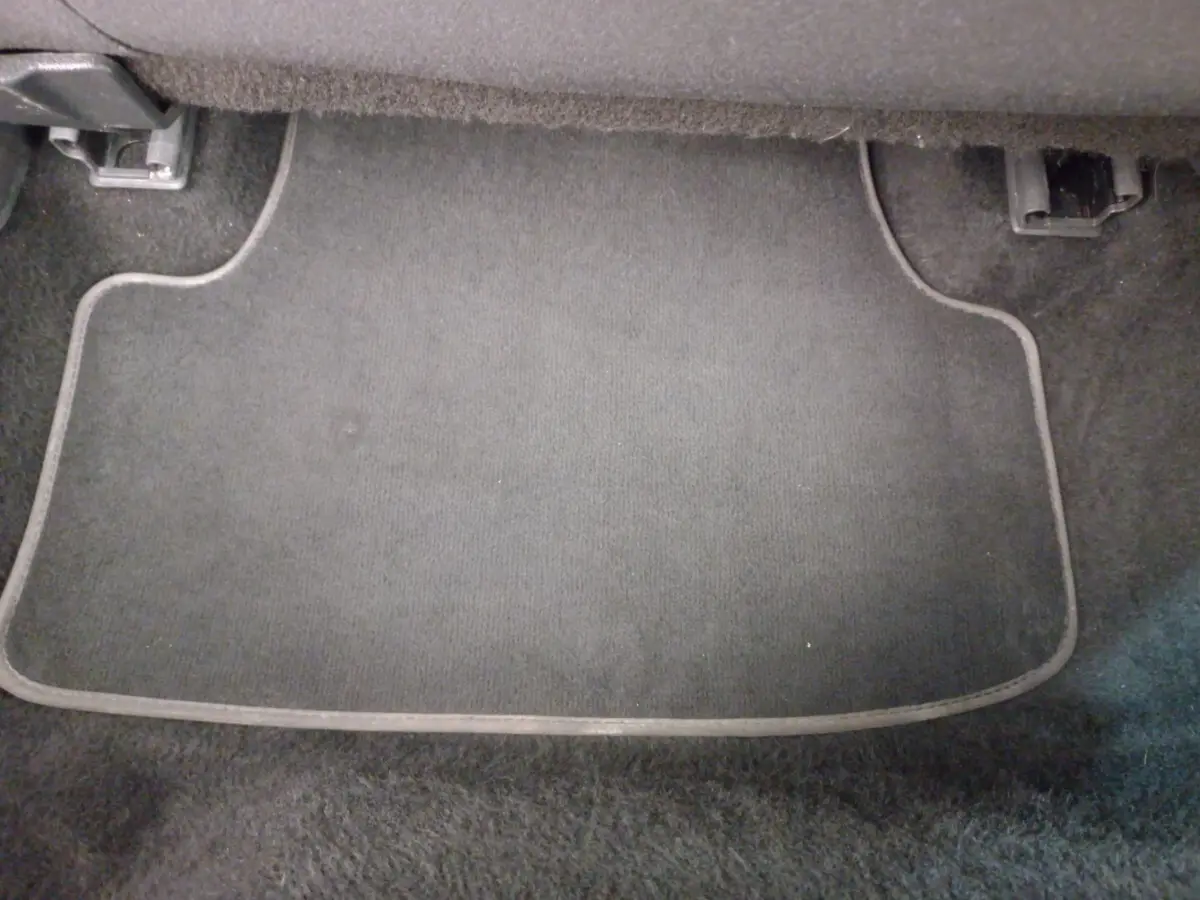 Tapis de sol noir côté passager avant d'une Volkswagen Golf gris foncé, vue rapprochée intérieure.