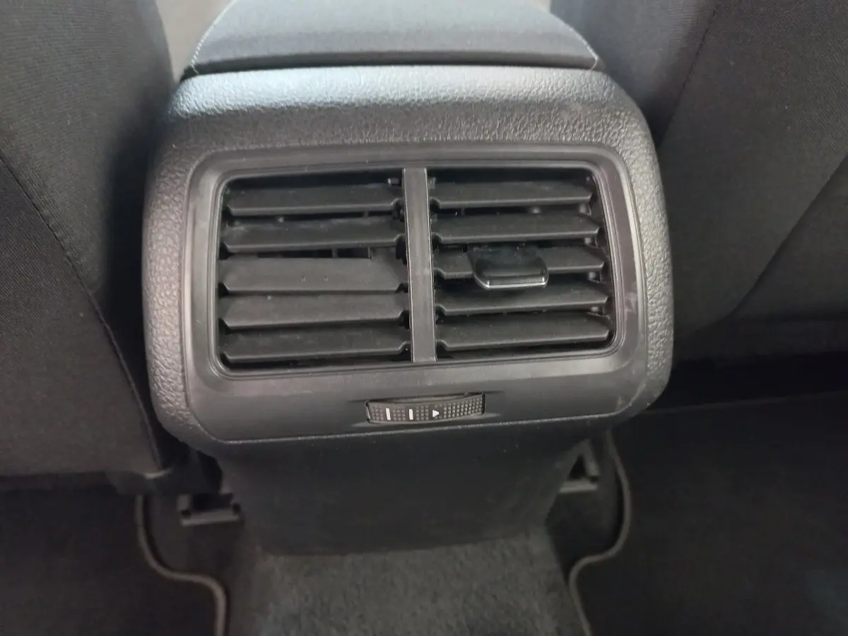 Grille d'aération arrière noire de la Volkswagen Golf gris foncé, vue centrée entre les sièges arrière.