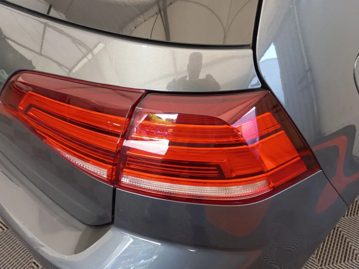 Gros plan sur le feu arrière droit rouge d'une Volkswagen Golf gris foncé, vue arrière en intérieur.