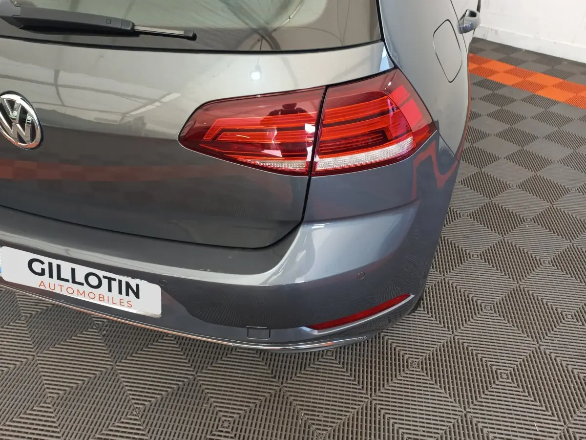 Vue rapprochée arrière droite d'une Volkswagen Golf gris foncé avec feux arrière LED et logo VW visible.