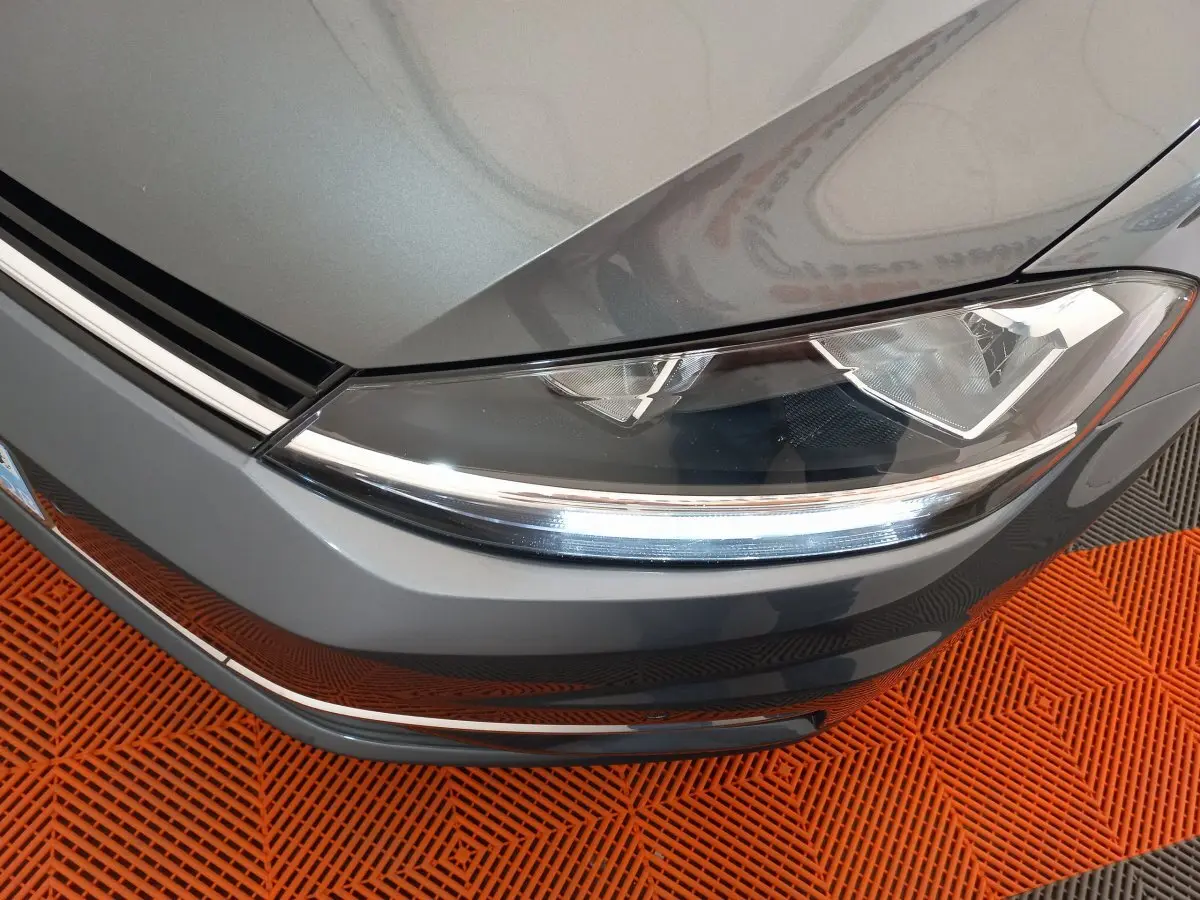 Gros plan sur le phare avant droit d'une Volkswagen Golf gris foncé 2019, avec détails LED et calandre visible.