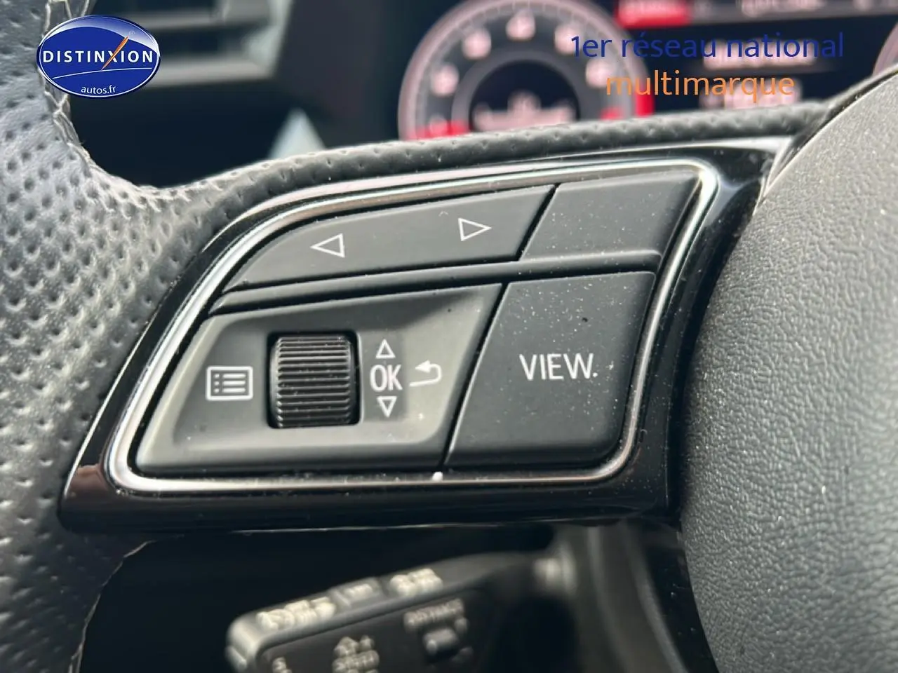 Gros plan sur les commandes multifonctions noires du volant cuir de l'Audi A3 Sportback 2024, version S line.