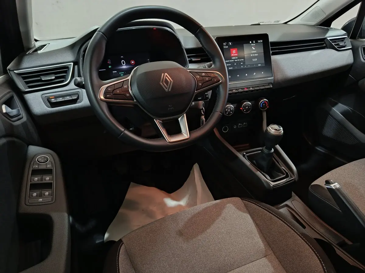 Intérieur avant de la Renault Clio Evolution Blue dCi 100 2025, volant cuir, écran tactile central et boîte manuelle.