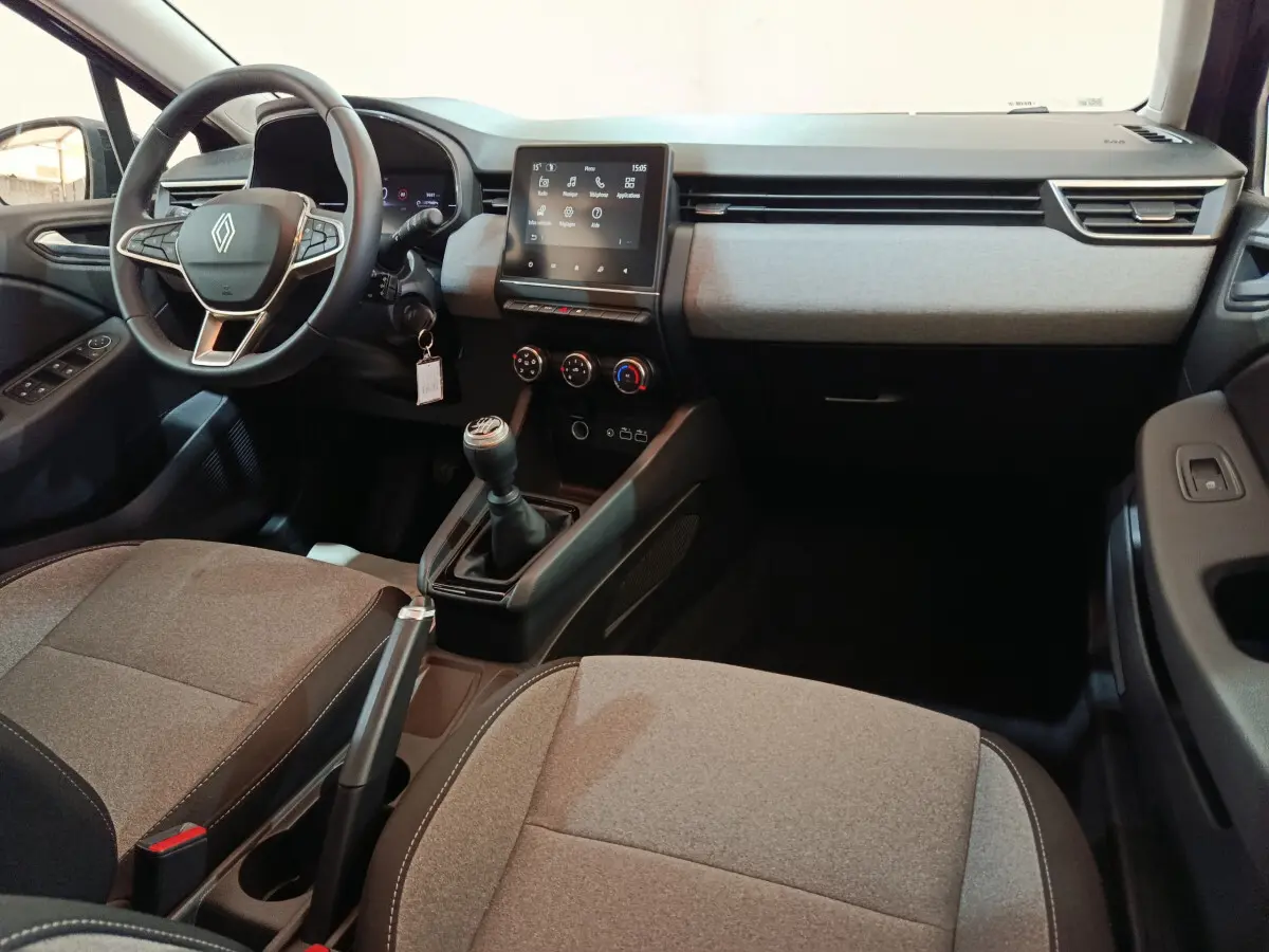 Intérieur avant de la Renault Clio Evolution Blue dCi 100 2025, vue côté conducteur, sièges gris et tableau de bord moderne.