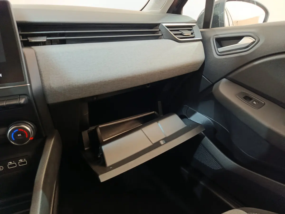 Intérieur côté passager de la Renault Clio Evolution Blue dCi 100 2025, boîte à gants ouverte et tableau de bord gris clair.