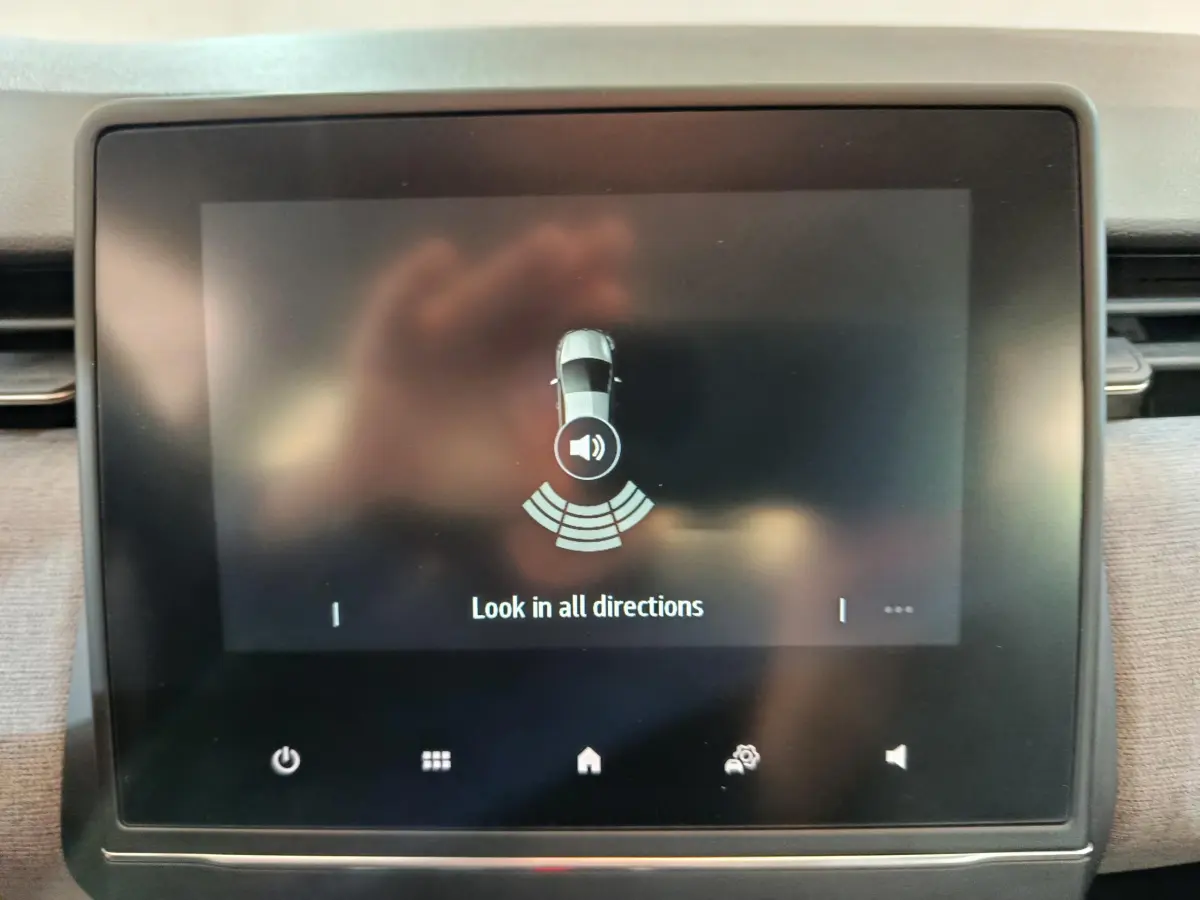 Écran tactile central de la Renault Clio 2025 affichant l'alerte de détection d'obstacles en stationnement.